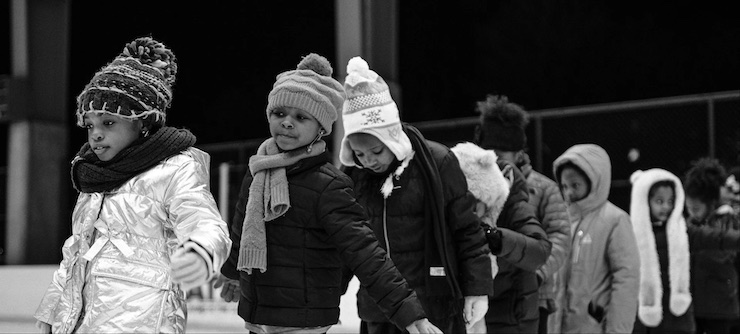 black girls in coats and hats, standing in line at an ice rink