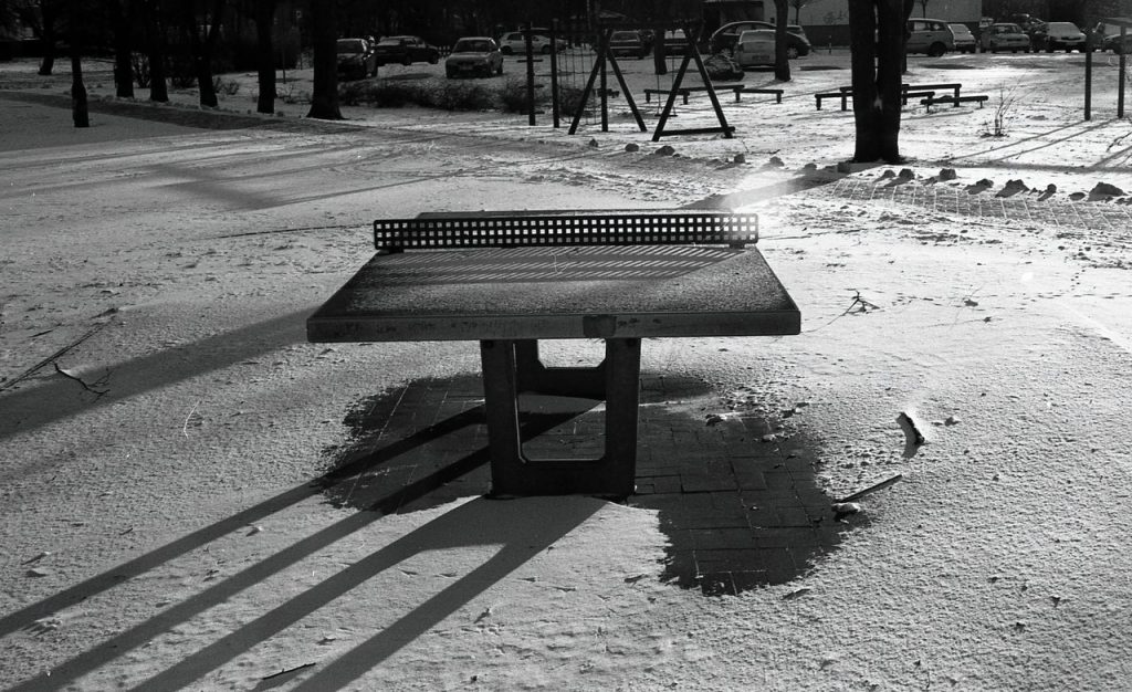 a greyscale photo of a outdoor ping pong table in the frost